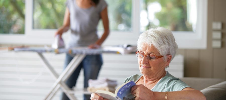 femme senior assise sur un canapé bouquinant près d'une femme